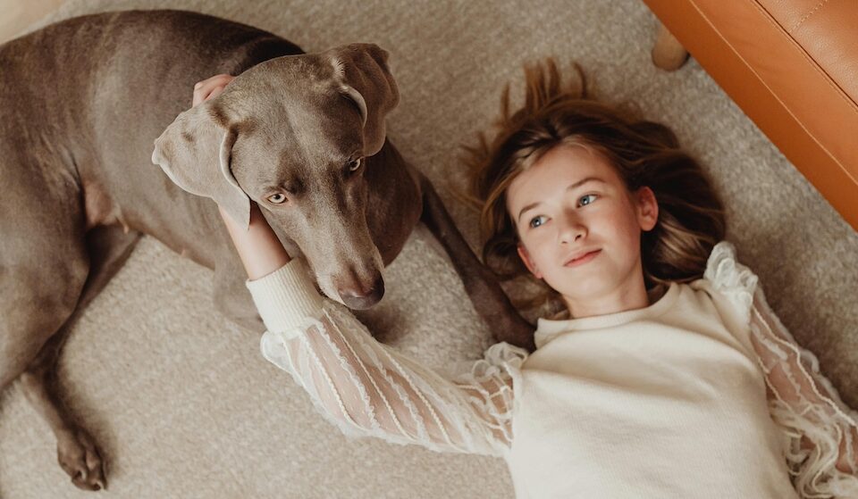 Child and her dog laying on a rug