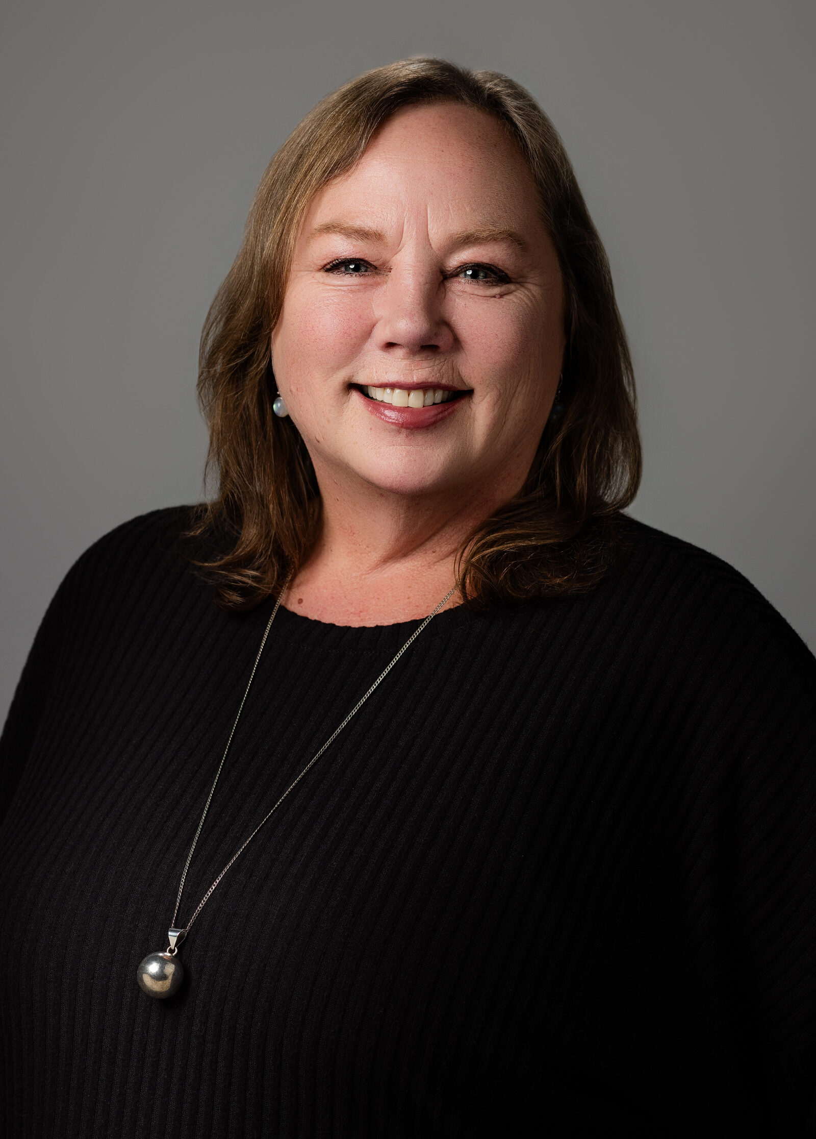 Professional headshot of a woman in a dark clothes against a neutral gray background | Senior Project Manager