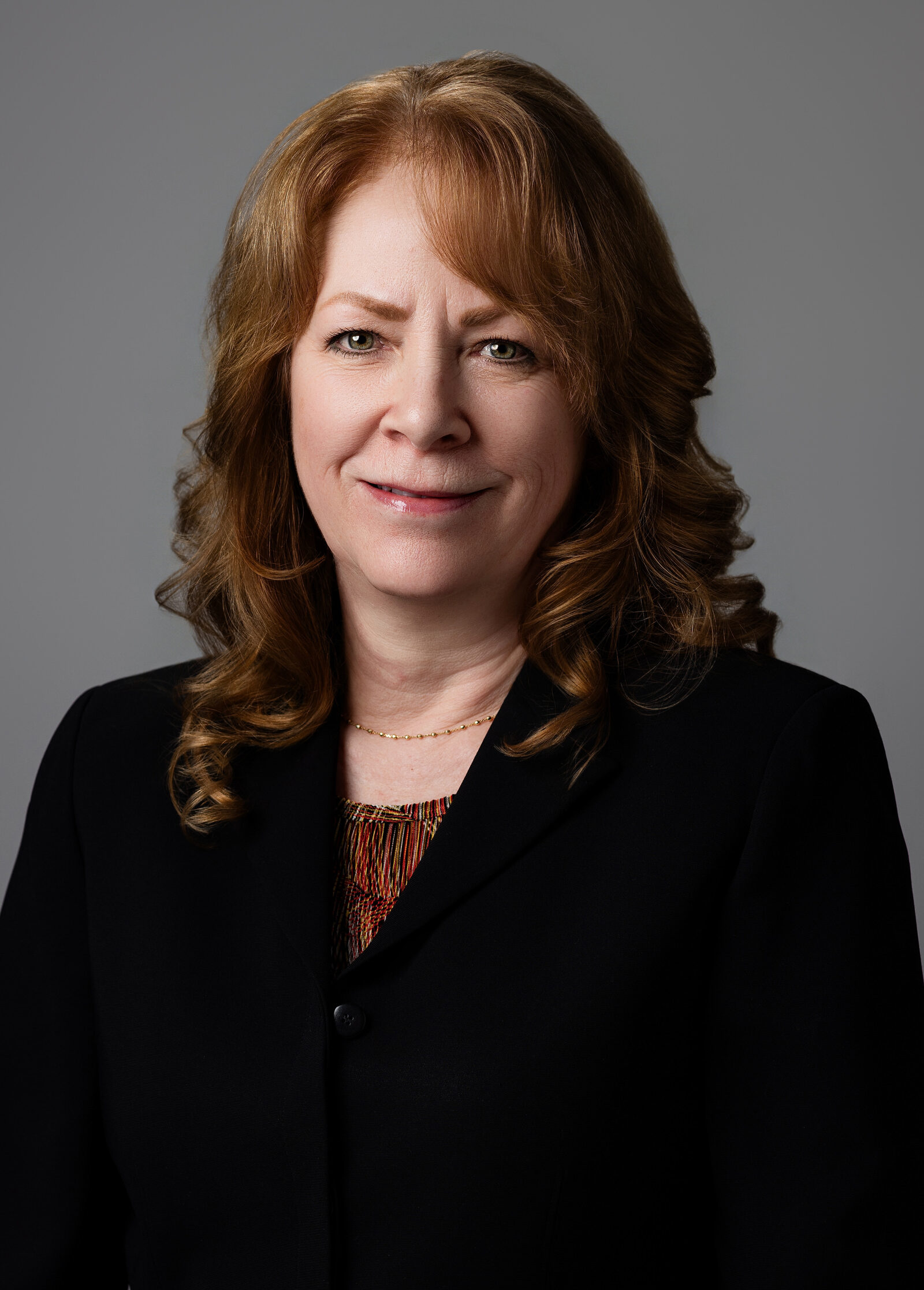 Professional headshot of a woman in a dark clothes against a neutral gray background | Senior Project Manager