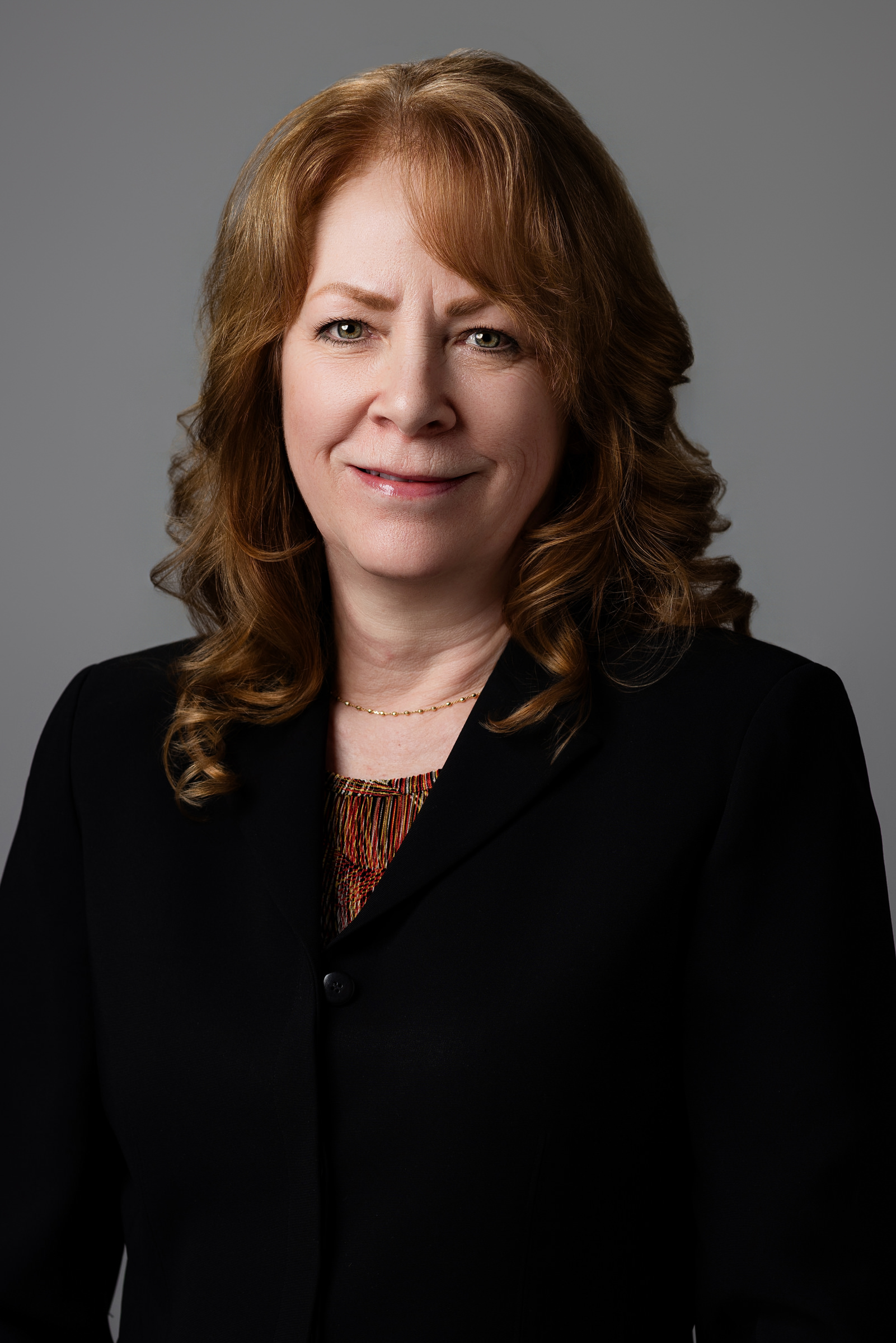 Professional headshot of a woman in a dark clothes against a neutral gray background | Senior Project Manager